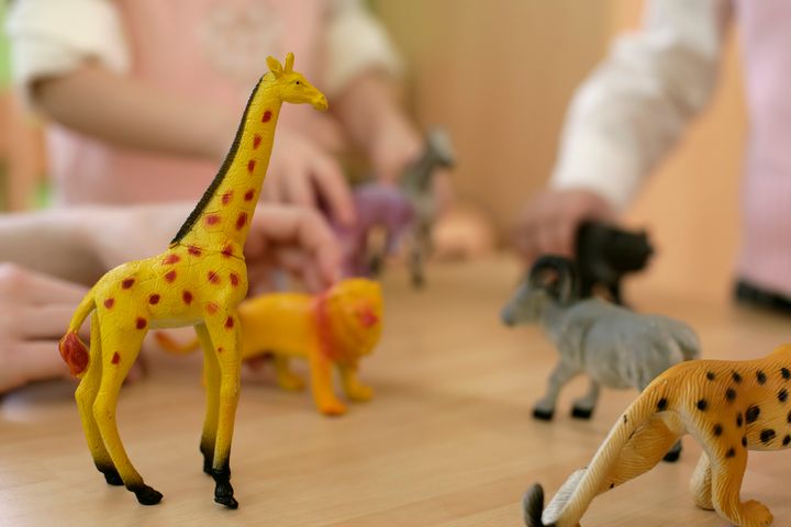 Mâini de copii jucându-se cu figurine de animale